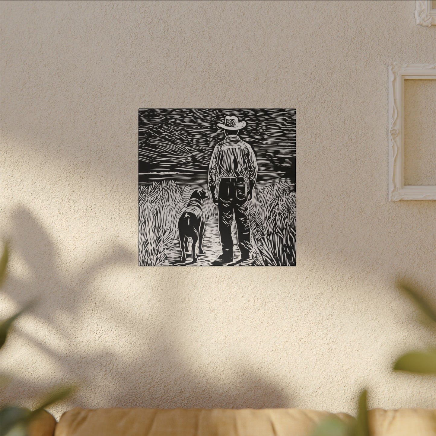 Alternate room view. Canvas print in linocut style showing a cowboy and his dog standing side by side on a country path, gazing toward the horizon in black and white.