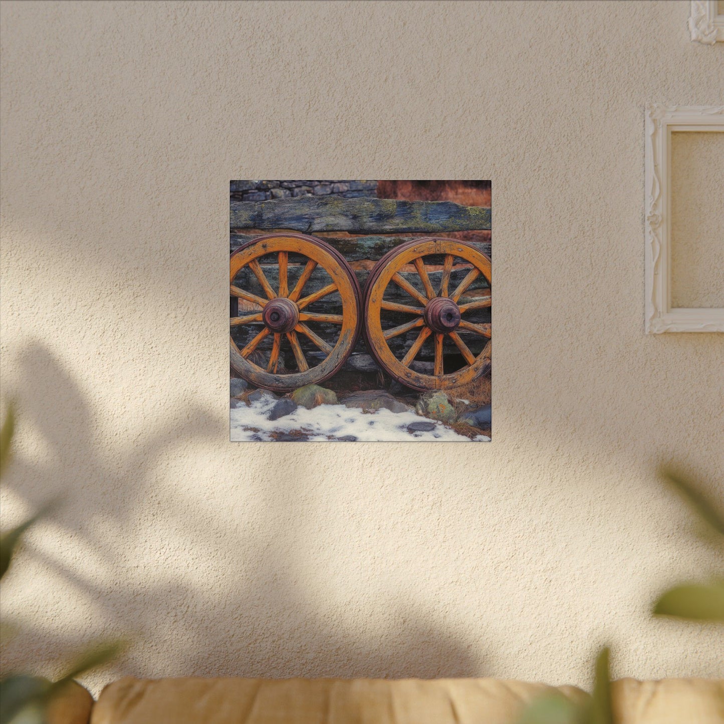 Alternate room view. Canvas print featuring two antique wooden wagon wheels leaning against a rustic fence, with snow and stone in the foreground and rich textures throughout.