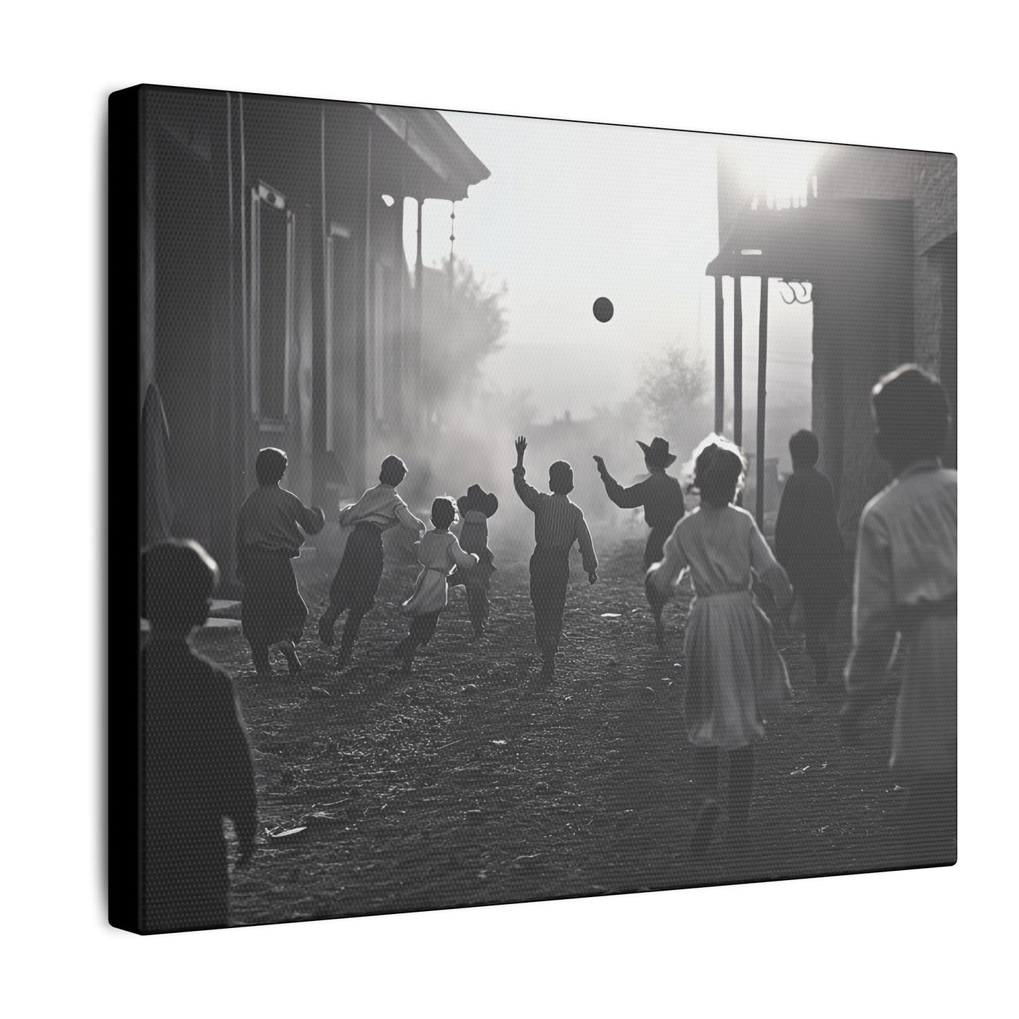 Black-and-white western street scene canvas print of children running and playing with a ball at sunset, capturing joyful movement and nostalgic charm, side view